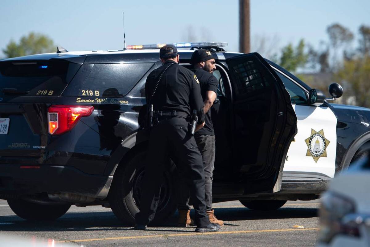 A man is escorted to a sheriff's vehicle after a shooting at the Sacramento Sikh Society Temple