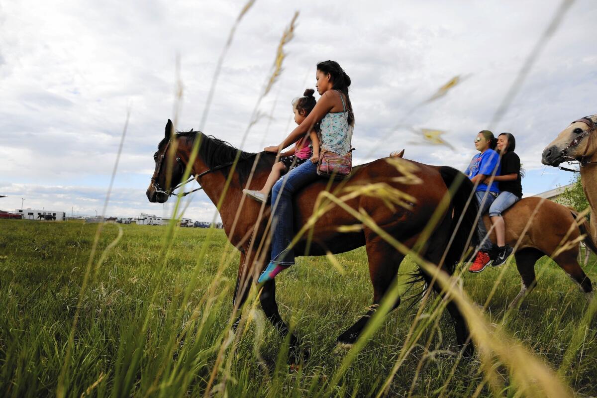 Courntey Little Nest gives her sister, Kadrean Iron, a ride on her horse. The Crow live on a 2.2 million-acre reservation in Montana, and have signed an agreement to mine 1.4 billion tons of coal on their land.
