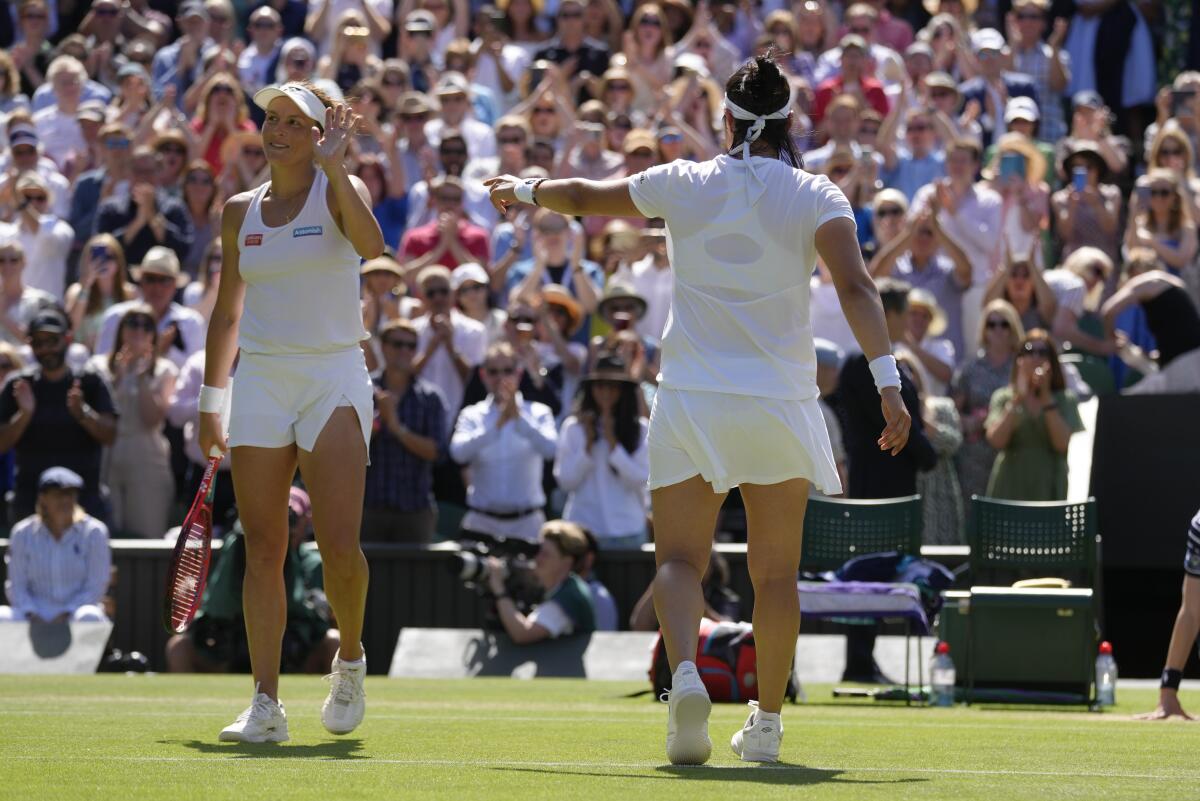 Tunisia's Ons Jabeur, right, gestures to Tatjana Maria to receive applause from the crowd 