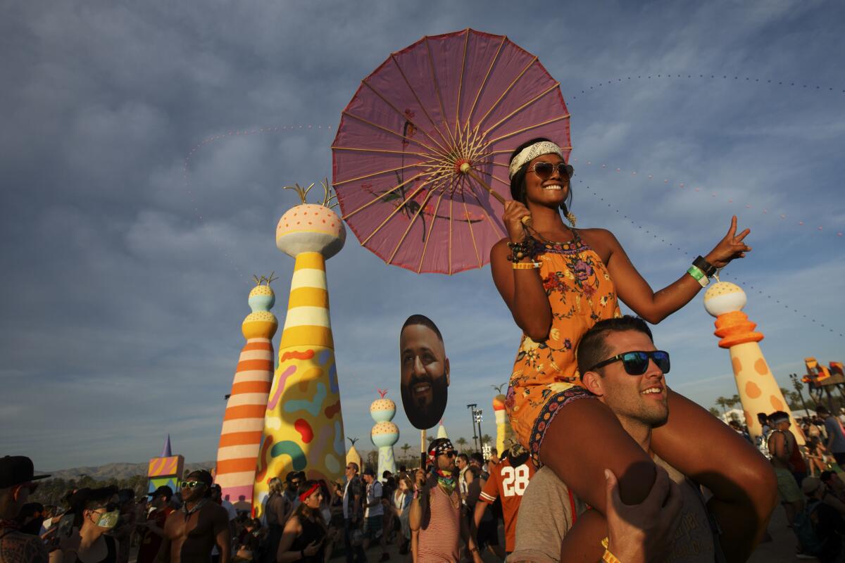 Marilou Stoltenberg, 33, of Hermosa Beach, holds an umbrella while riding on the shoulders of Justin Thompson, 37, of Long Beach, at the 2017 festival.