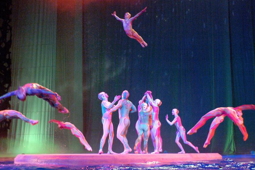Acrobats from "O" leap into a pool of water.
