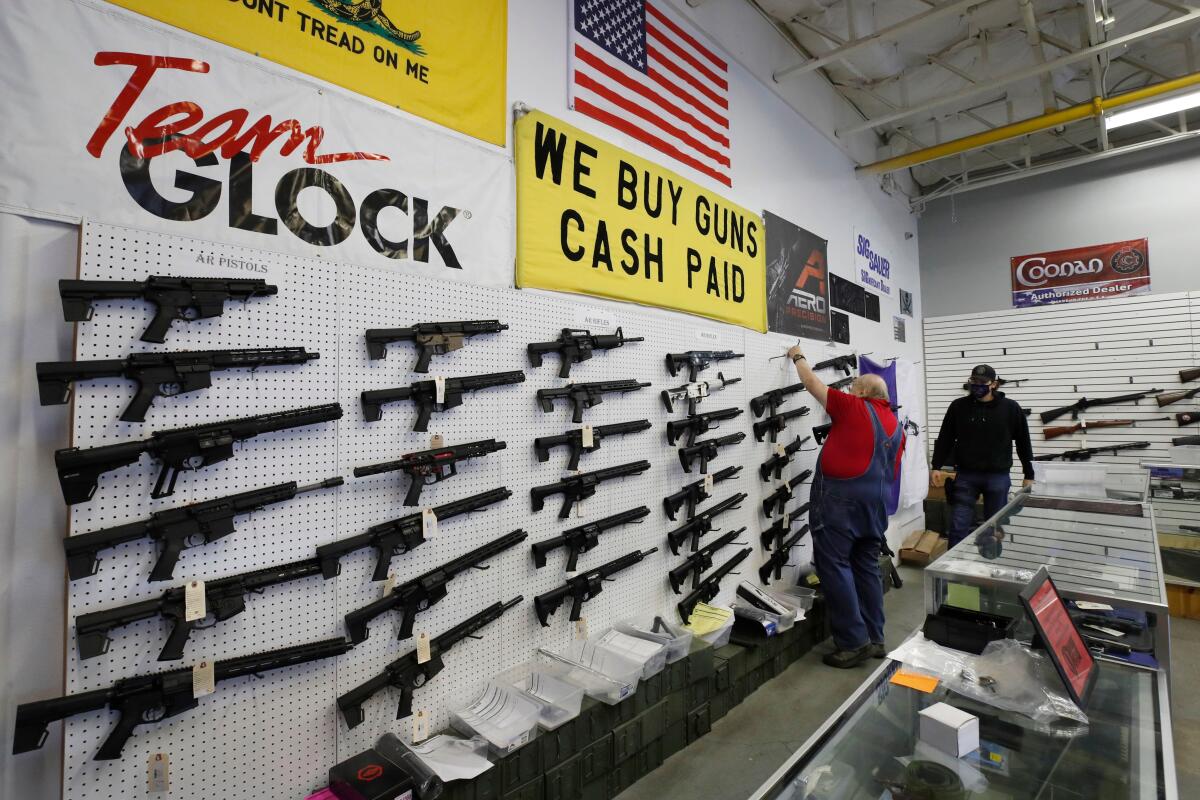 Workers arrange AR-15 style rifles on a wall that are for sale at Davidson Defense in Utah