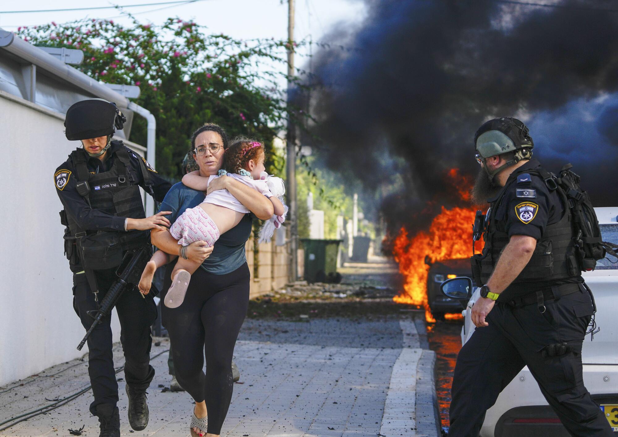 Police officers evacuate a woman and a child from a site hit by a rocket fired from the Gaza Strip, in Ashkelon