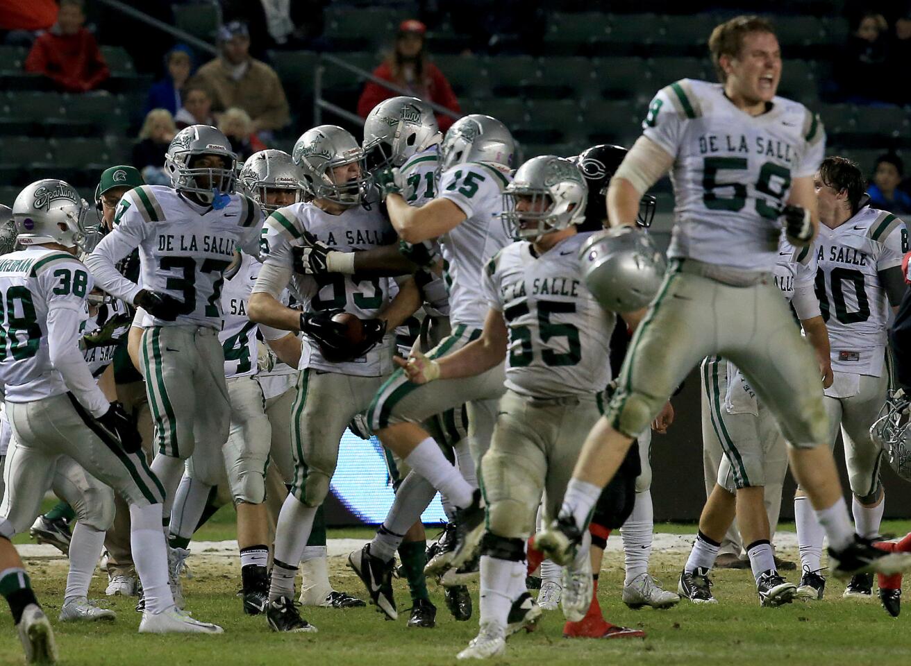 De La Salle linebacker Cameron Lissarrague is swarmed by teammates after his interception of Centennial quarterback Anthony Catalano in the third quarter of the CIF State Open Division bowl game Saturday at StubHub Center.