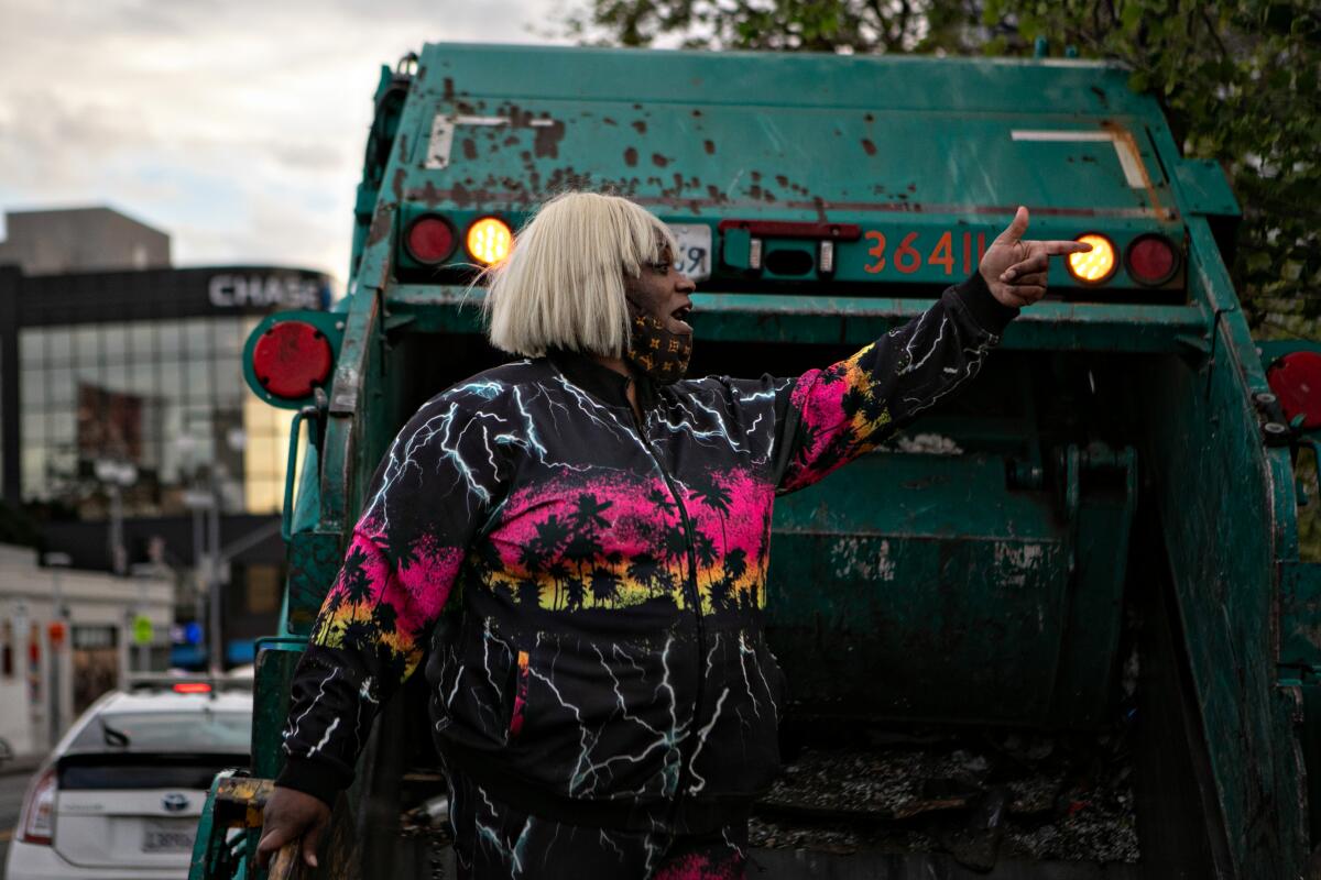 A woman stands near a garbage truck.