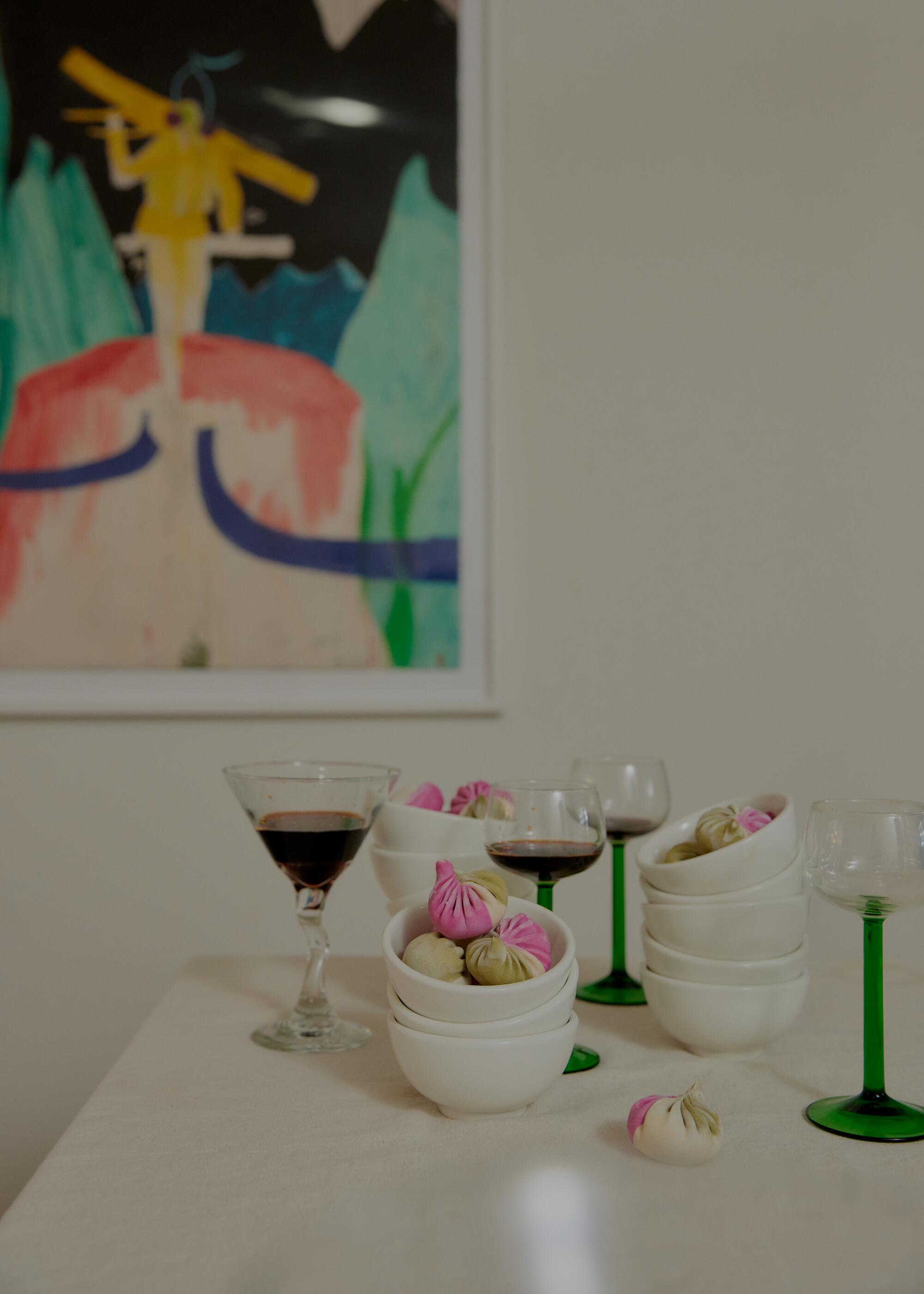 A sculptural offering of dumplings inside stacks traditional of rice bowls, with accompanying glasses of soy sauce.