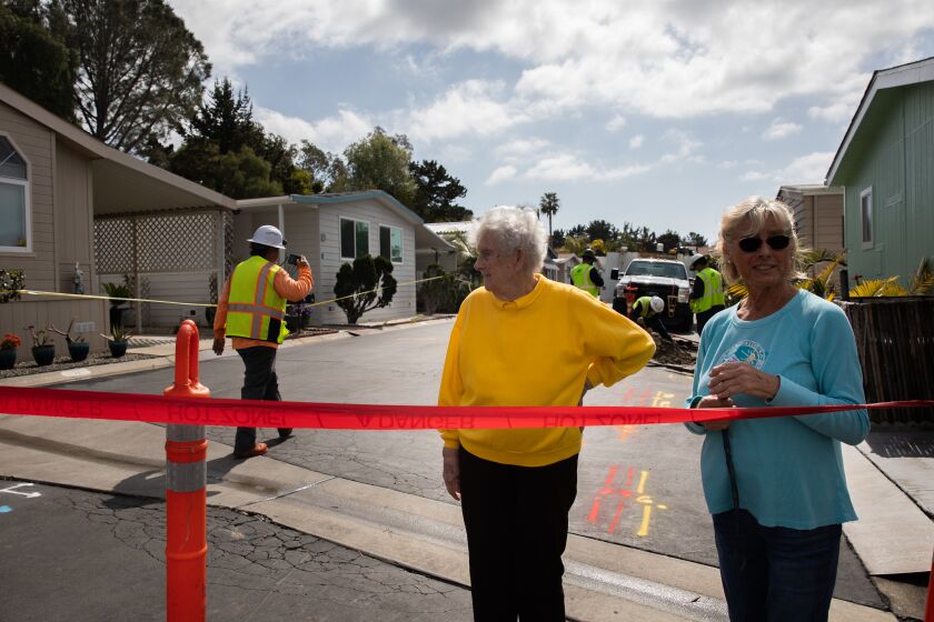 Vista, CA - March 16: Brenda Stebbings (right) and her mom Daphne Swanson (left) watch as SDG&E workers cut the gas line to several homes along Green Valley Mobile Home Park near Sky Haven Lane in Vista, CA on Thursday, March 16, 2023. Dozens of families were forced to evacuate after part of Sky Haven Lane, up the hill, began to buckle and caused a bluff collapse. Stebbings, who lives across the street from her home, was forced to evacuate. (Adriana Heldiz / The San Diego Union-Tribune)