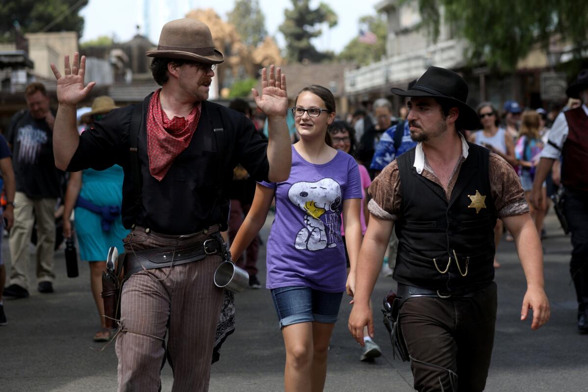 Knott's Berry Farm guest Hanna Cormack, center, of Sanger, escorts Scruff Mayfield, left, along with deputy sheriff Hayden Allcorn to a hearing in Ghost Town Alive!