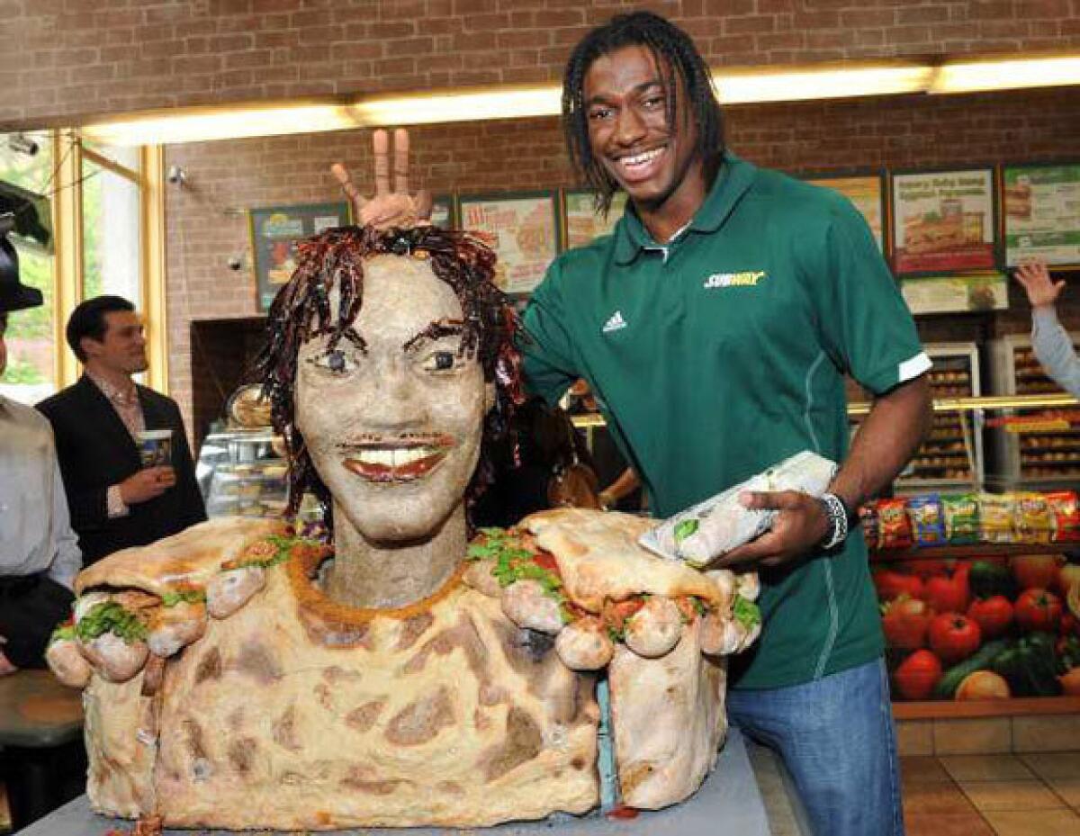 Robert Griffin III poses with a statue of him made of Subway Smokehouse BBQ chicken.