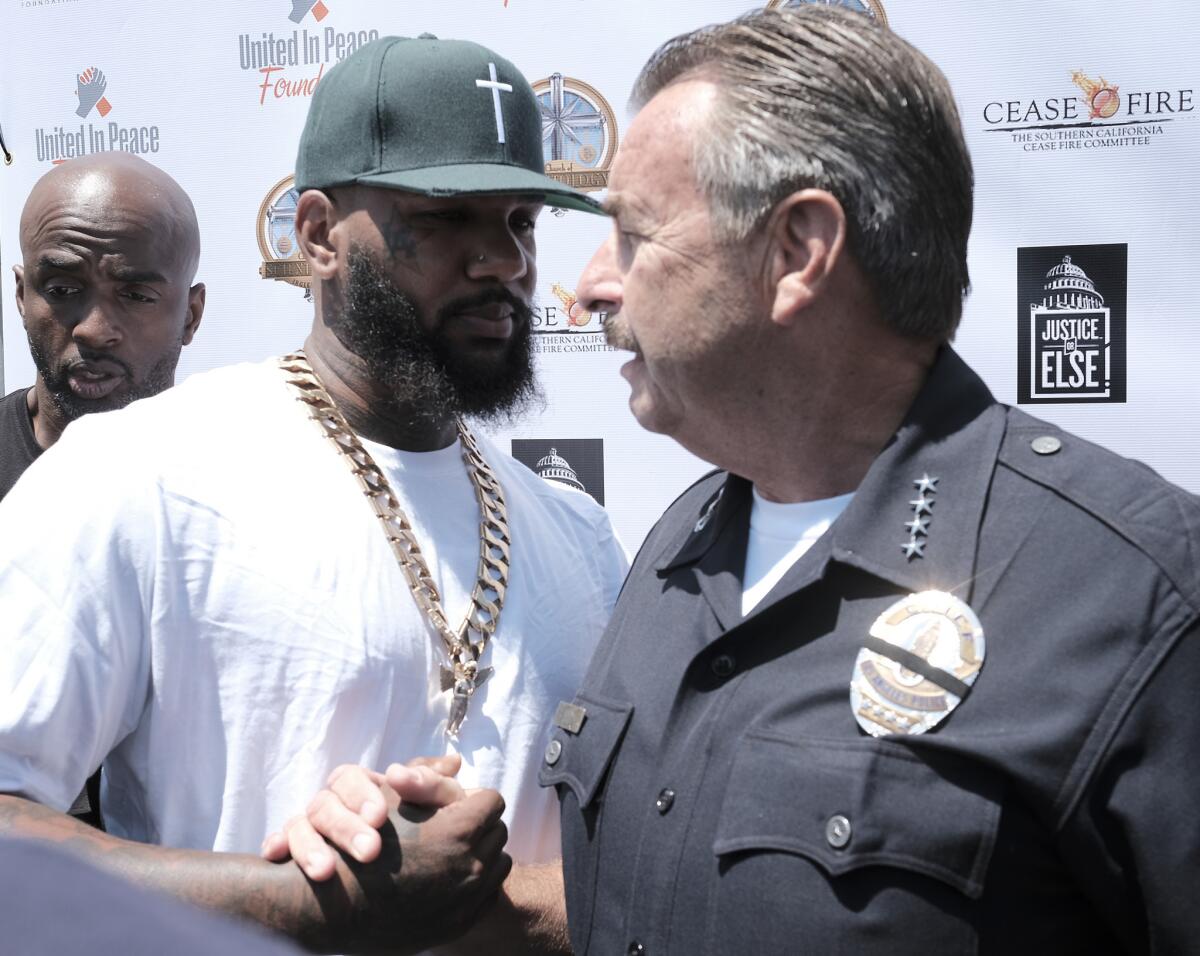 The Game, left, talks with Los Angeles Police Chief Charlie Beck during "Time to Unite: United Hoods + Gangs Nation," a community summit organized by rappers The Game and Snoop Dogg in South Los Angeles.