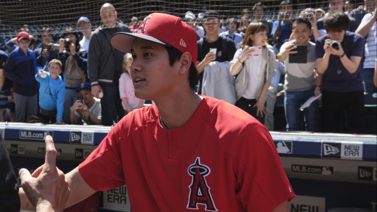 Angels designated hitter Shohei Ohtani is photographed by fans before a game against the host Seattle Mariners on June 1.