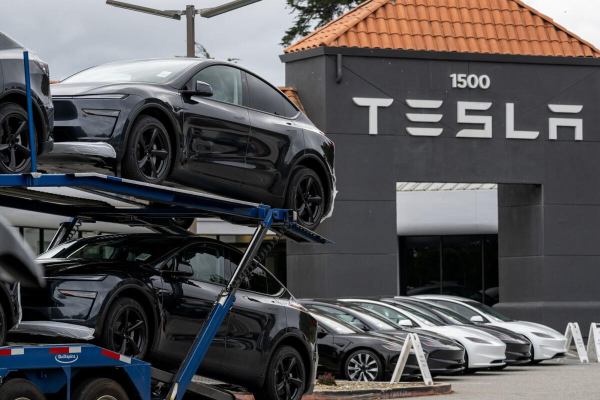 A vehicle transport truck arrives with Tesla Model Y vehicles at the company's store in Colma.