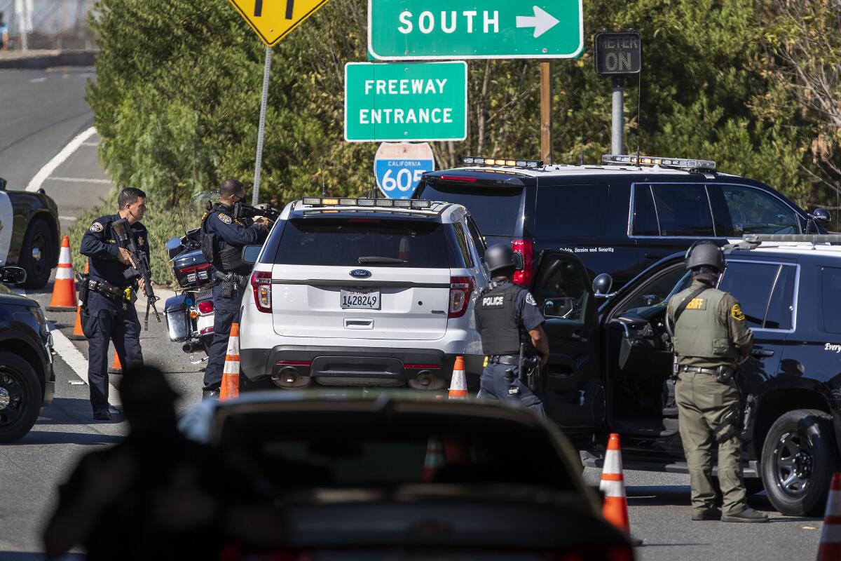 Officers with rifles stand behind police SUVs next to a freeway onramp