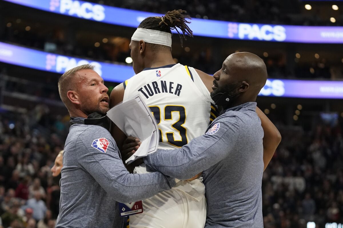 Indiana Pacers center Myles Turner, center, is pulled from a fight with Utah Jazz center Rudy Gobert in the second half during an NBA basketball game Thursday, Nov. 11, 2021, in Salt Lake City. Turner and Gobert were ejected from the game. (AP Photo/Rick Bowmer)