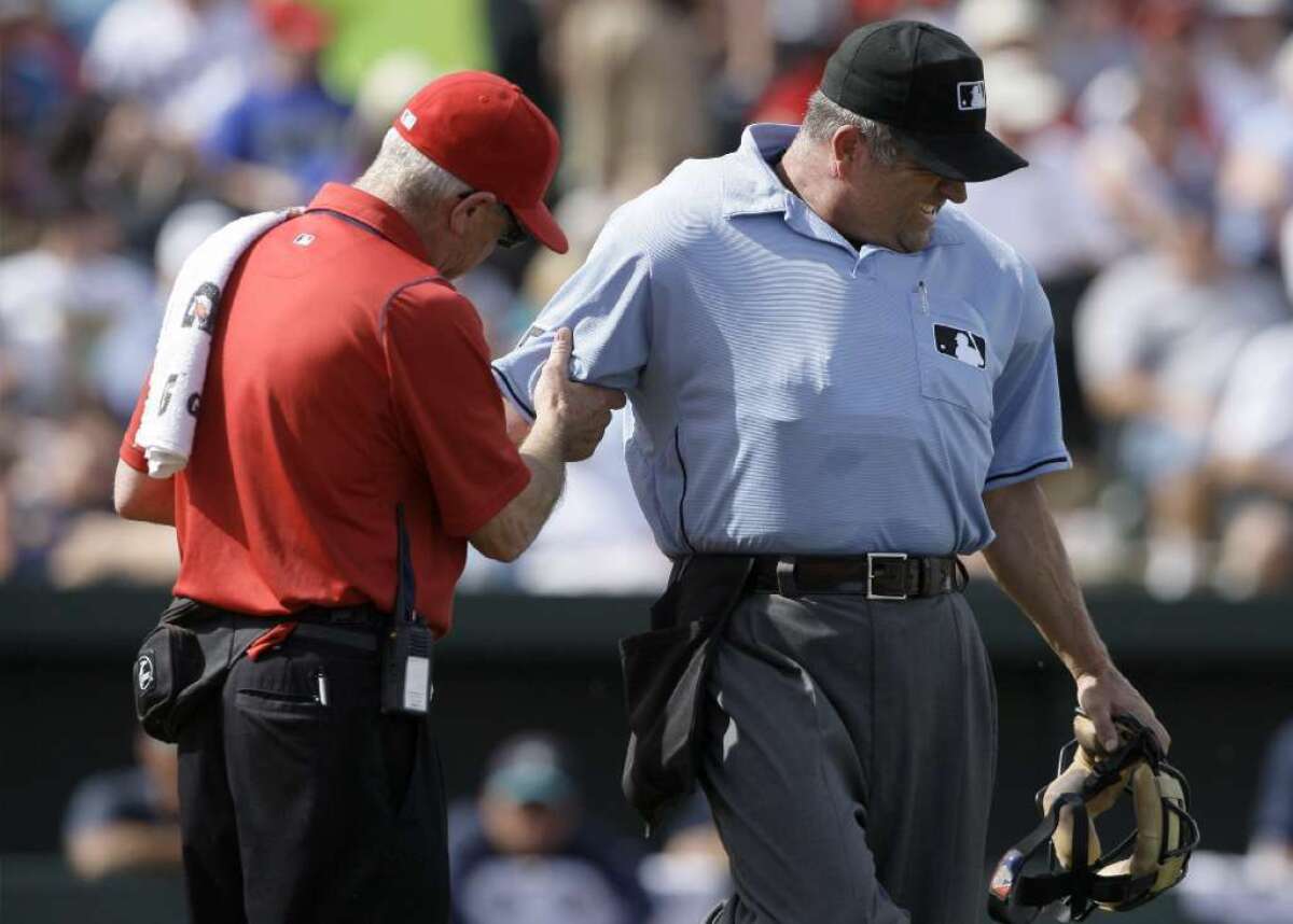 Umpire Dale Scott is checked by a trainer after being hit by a pitch.