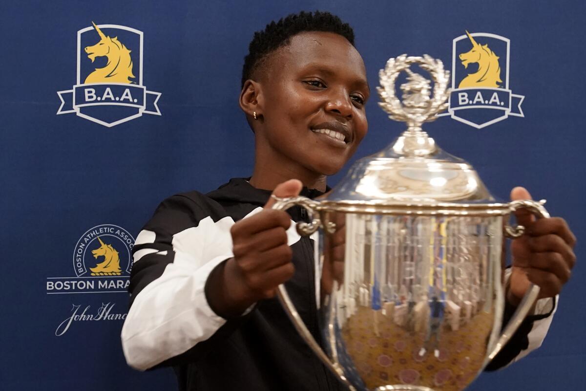FILE - Diana Kipyokei, of Kenya, holds a Boston Marathon championship trophy following a news conference, on Oct. 12, 2021, in Boston. Kipyokei was suspended on Friday Oct. 14, 2022 after testing positive for doping at the 2021 race she won and allegedly obstructing an investigation. (AP Photo/Steven Senne, File)