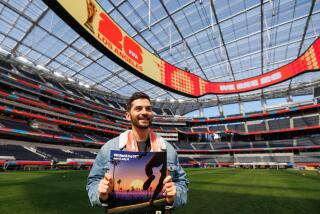 Artist Thieb Delaporte-Richard stands at SoFi Stadium and holds up a L.A. 2026 World Cup poster that features his work. 
