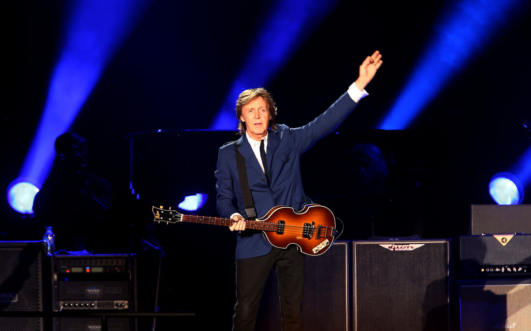 A man with a bass guitar waves at the crowd.