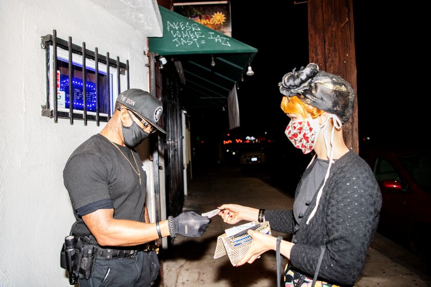 LOS ANGELES, CA - JULY 30: Security officer Don McClaren checks for proof of vaccination status from customers before they can enter the bar inside Permanent Records Roadhouse on Friday, July 30, 2021 in Los Angeles, CA. (Mariah Tauger / Los Angeles Times)