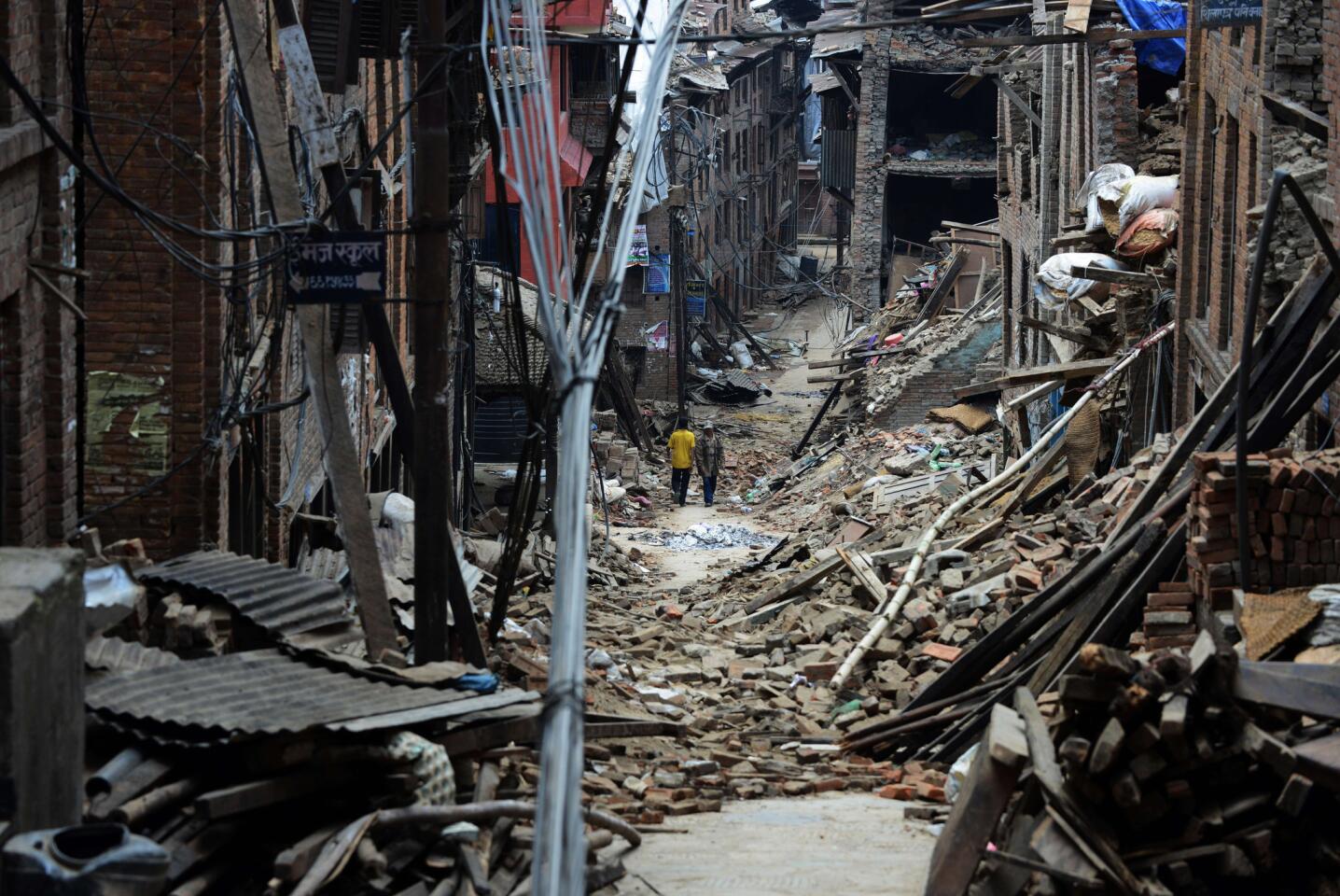 Nepalese residents walks past damaged houses following an earthquake in Bhaktapur on the outskirts of Kathmandu on May 13, 2015.