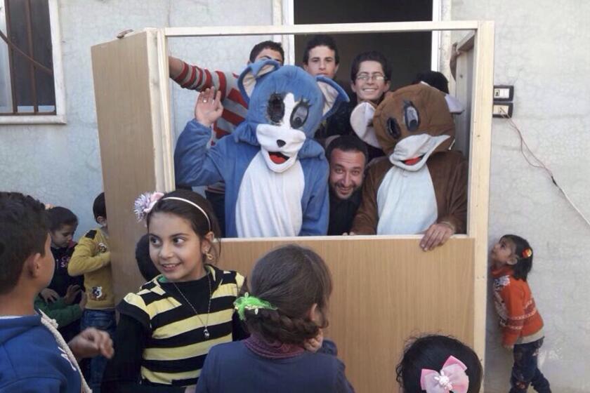 Ahmad Khatab (center) is flanked by performers dressed as cartoon cat and mouse duo Tom and Jerry at a childrens' performance of the Saraqib Youth Group theater troupe in Saraqib, Syria. The group formed in 2006 and has continued performing throughout the Syrian civil war.