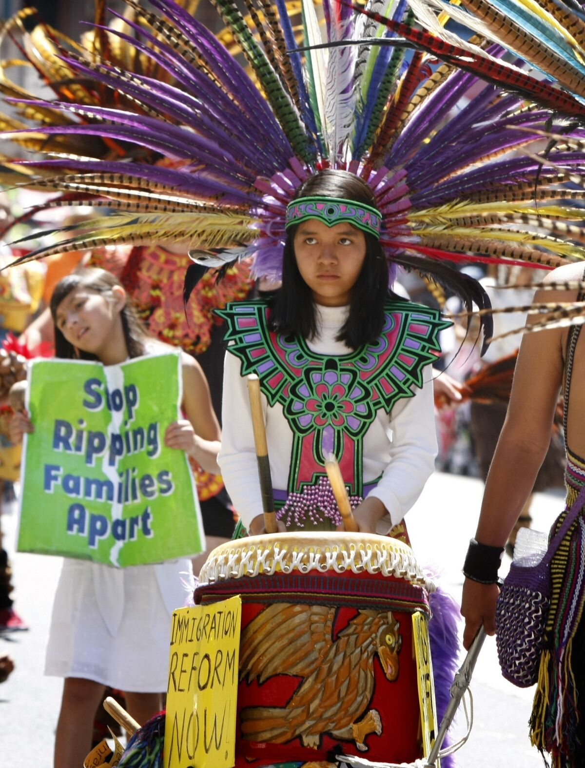 A young costumed member of the Aztec dance group beats a drum during a May Day march downtown. The group is often seen at L.A. street protests.
