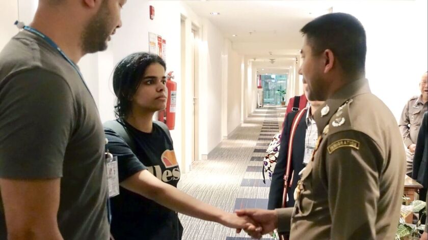 Rahaf Mohammed Alqunun, 18, shakes hands with Thai immigration chief Surachate Hakparn at a transit hotel at Bangkok's international airport on Jan. 7, 2019.