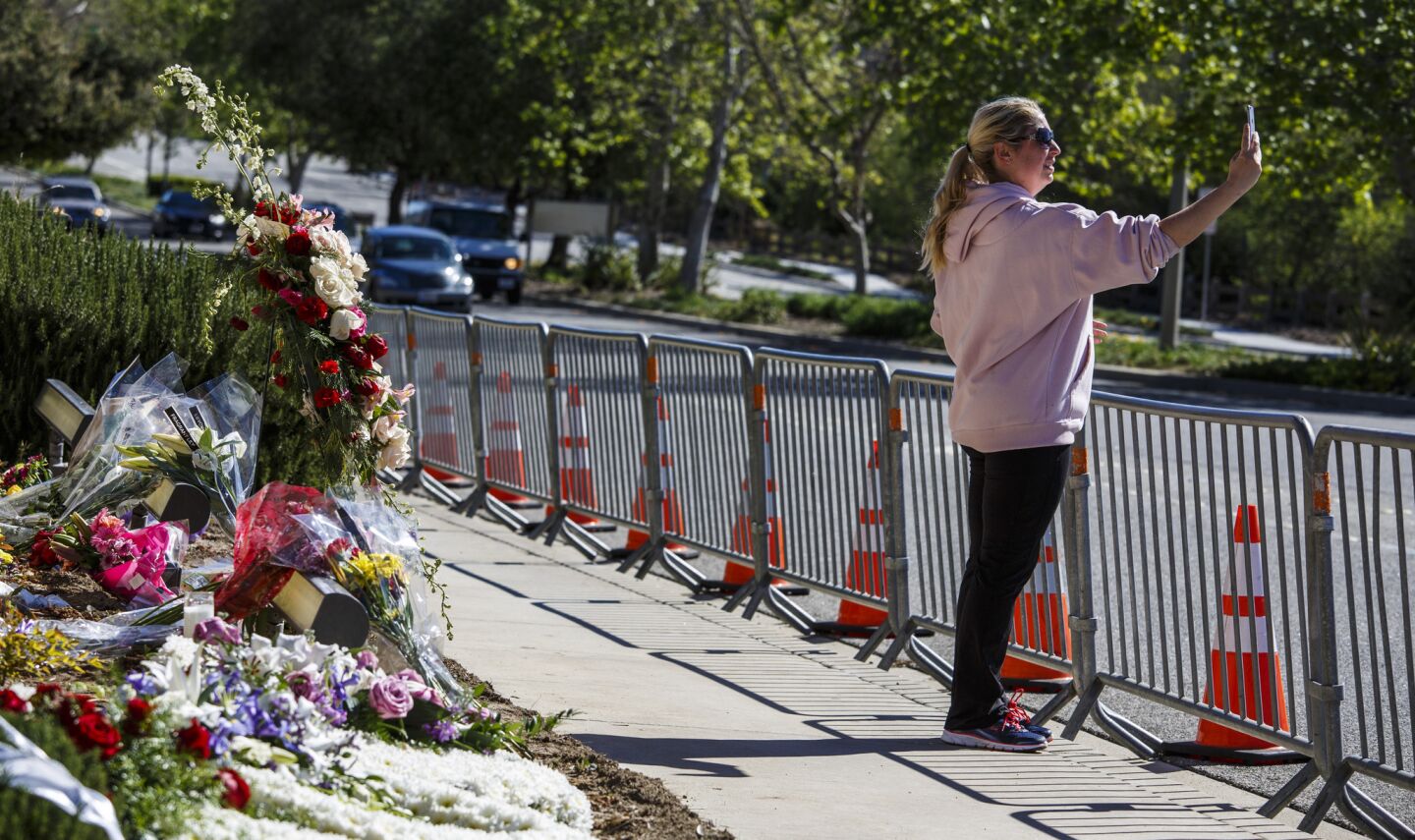 A woman takes a selfie at the entrance to the Ronal Reagan Presidential Library waiting for the motorcade bringing Nancy Reagan's body to lie in repose.