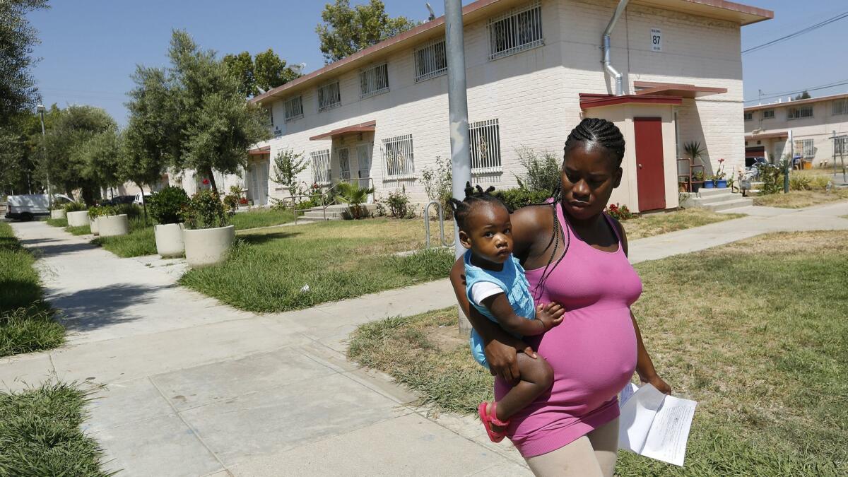 A woman and her child walk home in the Ramona Gardens housing project in Boyle Heights in July 2016.