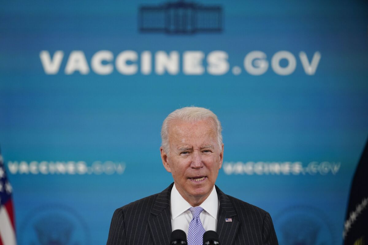 President Biden talks while standing in front of a backdrop with vaccines.gov on it.