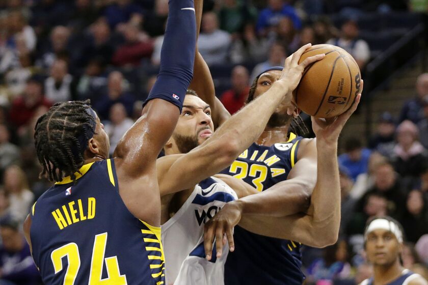 Minnesota Timberwolves center Rudy Gobert (27) shoots between Indiana Pacers guard Buddy Hield (24) and center Myles Turner (33) during the second quarter of an NBA basketball game Wednesday, Dec. 7, 2022, in Minneapolis. (AP Photo/Andy Clayton-King)