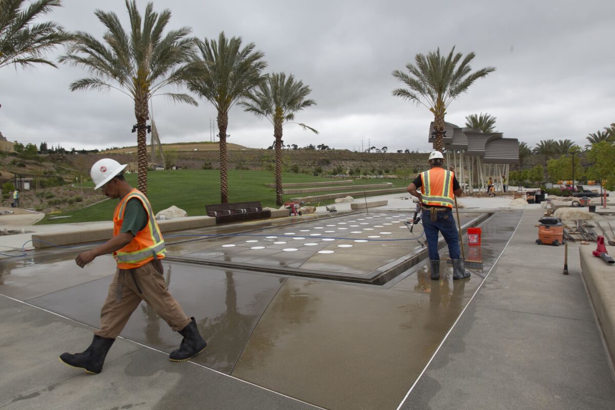 Workers clean the cement around the interactive water feature at the interactive fountain.