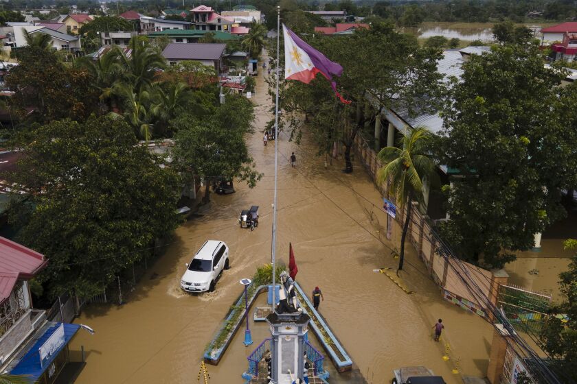 Residents pass by a flooded road from Typhoon Noru in San Miguel town, Bulacan province, Philippines, Monday, Sept. 26, 2022. Typhoon Noru blew out of the northern Philippines on Monday, leaving some people dead, causing floods and power outages and forcing officials to suspend classes and government work in the capital and outlying provinces. (AP Photo/Aaron Favila)