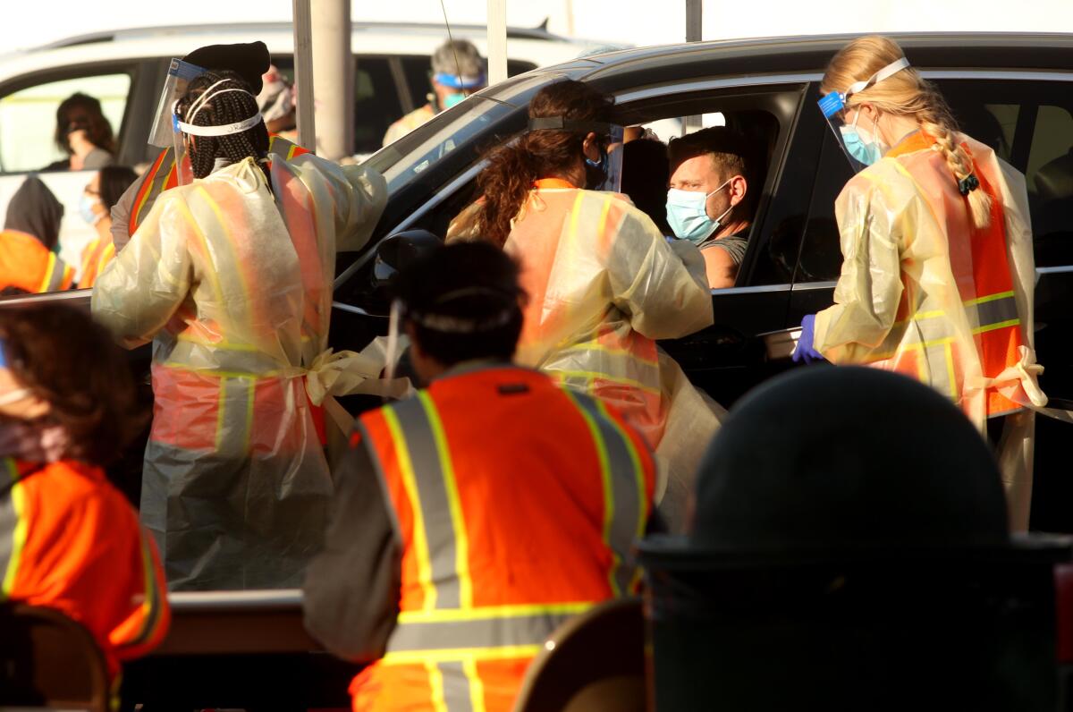 Medical workers tend to people waiting in their cars at a COVID-19 vaccine site at Cal State Northridge on Tuesday. 