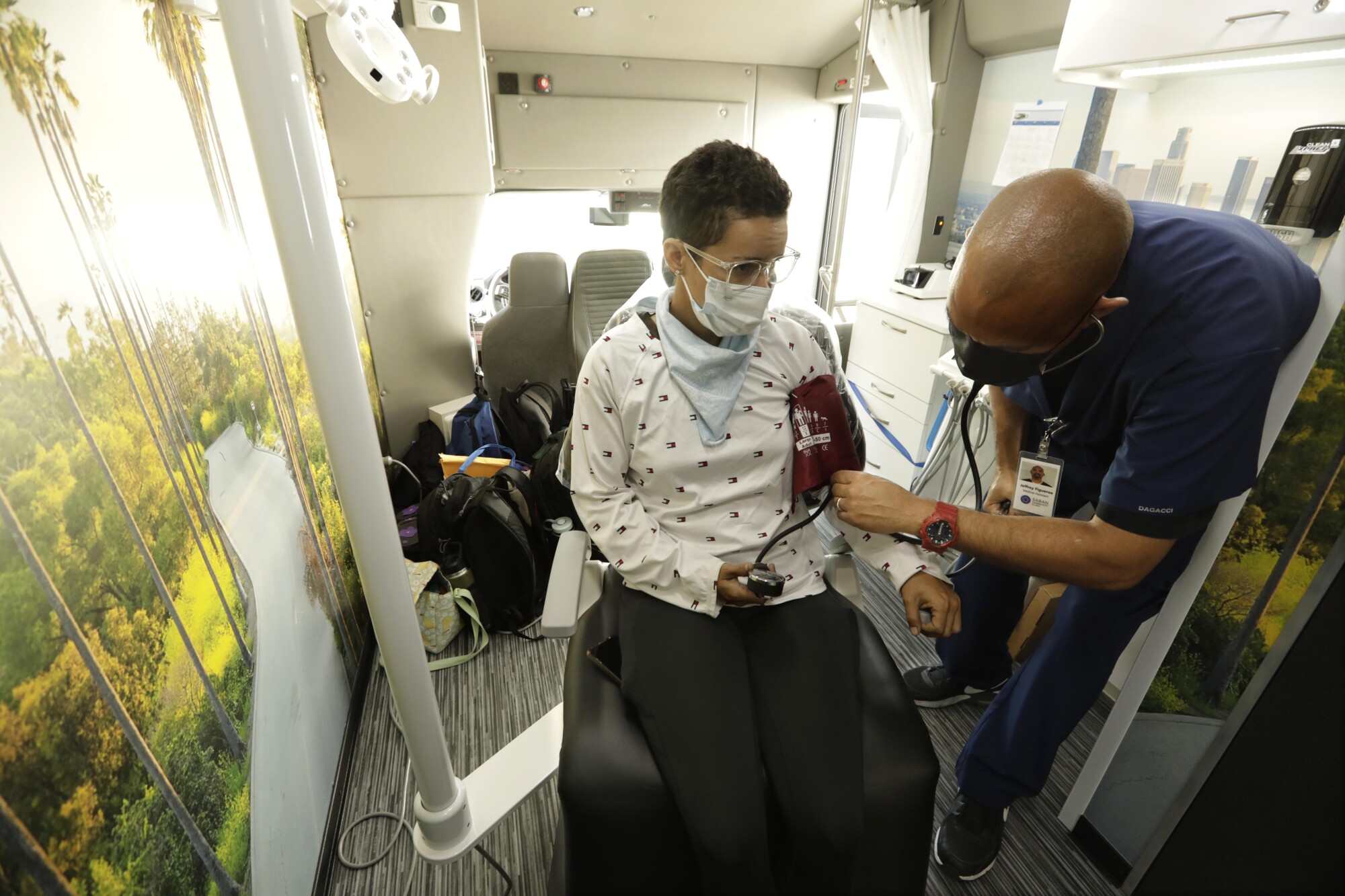 Jeffrey Figueroa takes the blood pressure of homeless patient Fabiola Perla inside the Saban Community Clinic mobile unit.