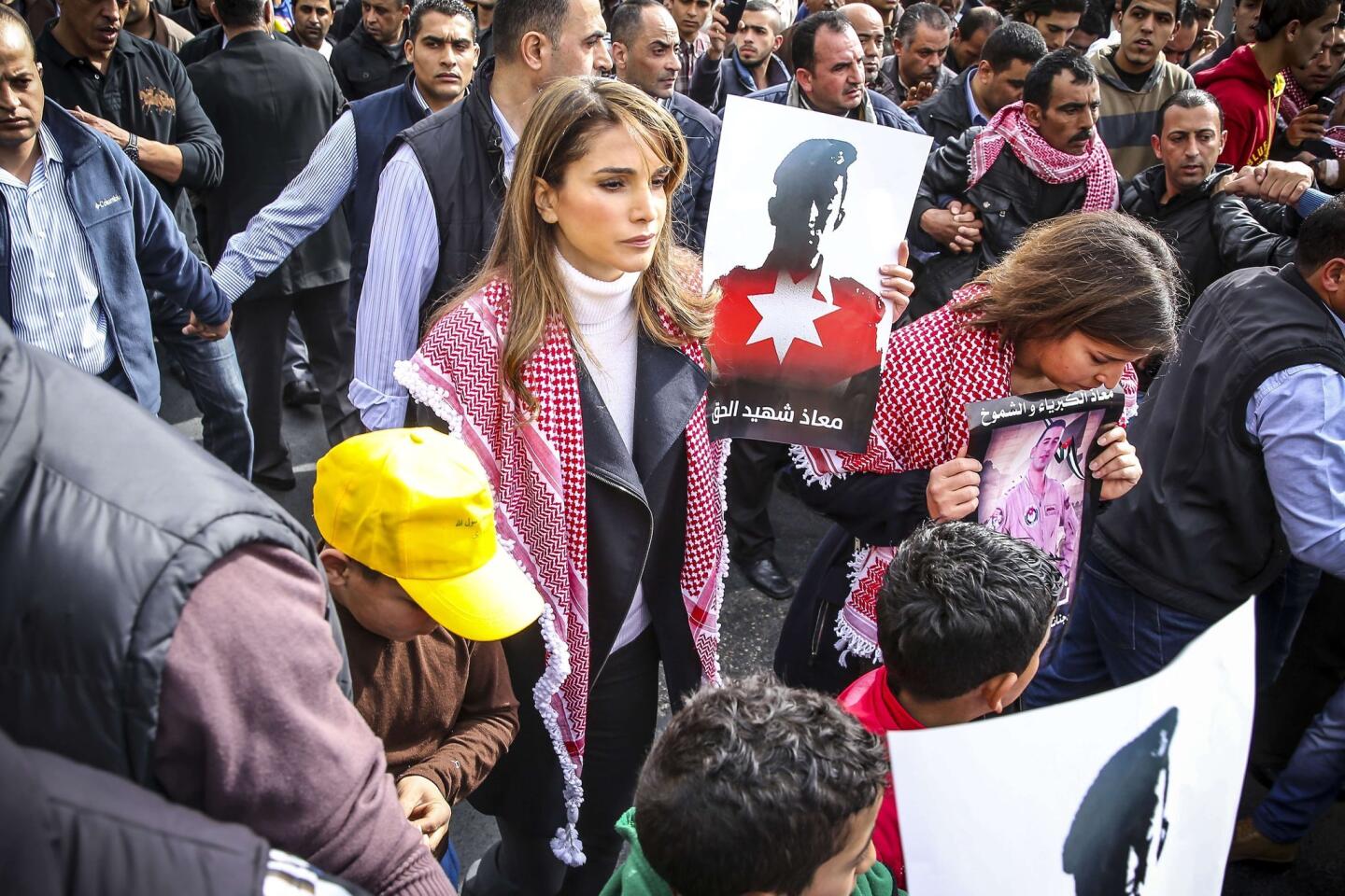 A photograph distributed Friday by the office of Jordanian Queen Rania shows the queen, at center, holding a placard during a rally in Amman to express solidarity with the pilot slain by Islamic State.