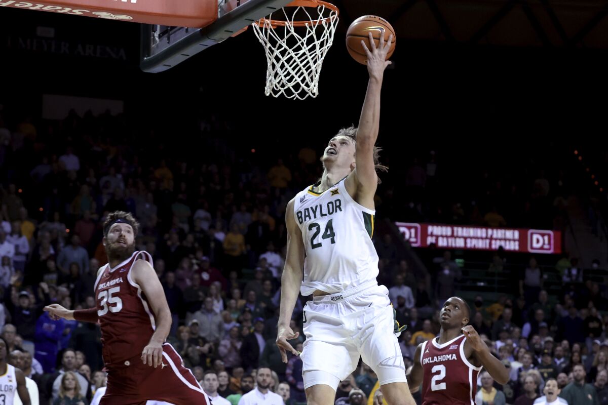 Baylor guard Matthew Mayer scores in front of Oklahoma forward Tanner Groves during the second half of an NCAA college basketball game Tuesday, Jan. 4, 2022, in Waco, Texas. (AP Photo/Jerry Larson)