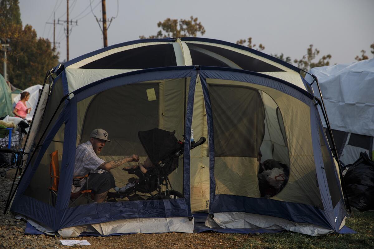 Camp fire evacuees now have rain to contend with as they occupy tents in a Walmart parking lot in Chico, Calif.