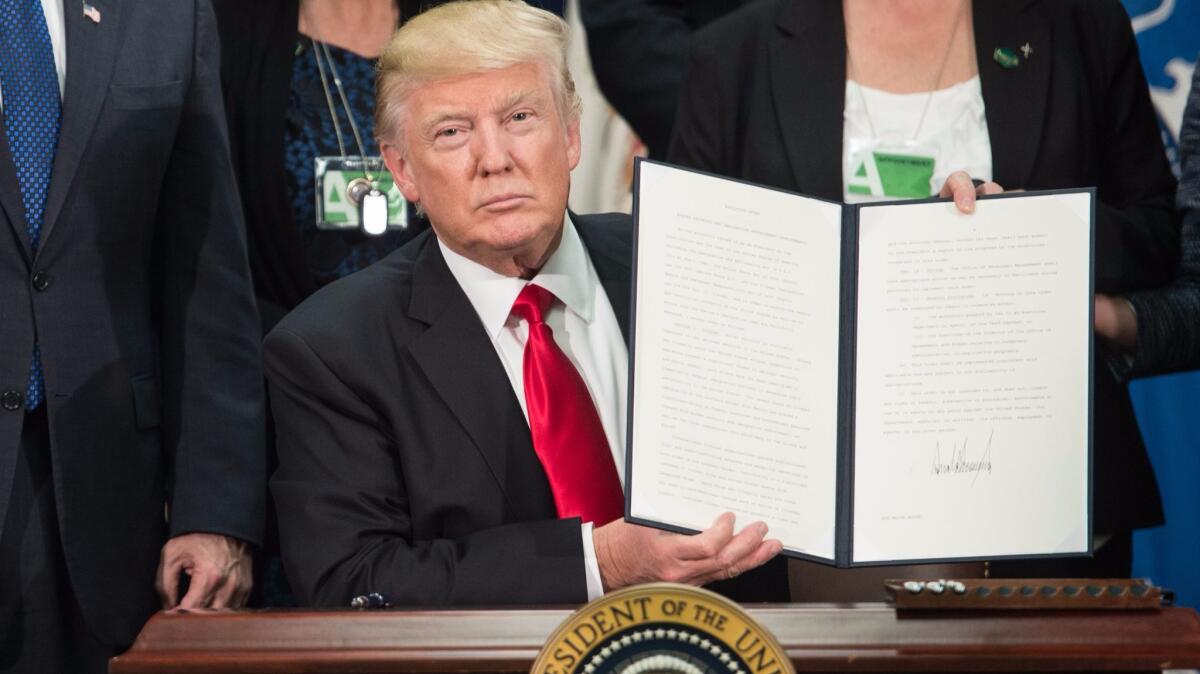 President Trump signs an executive order to start the Mexico border wall project on Jan. 25. (Nicholas Kamm / AFP/Getty Images)