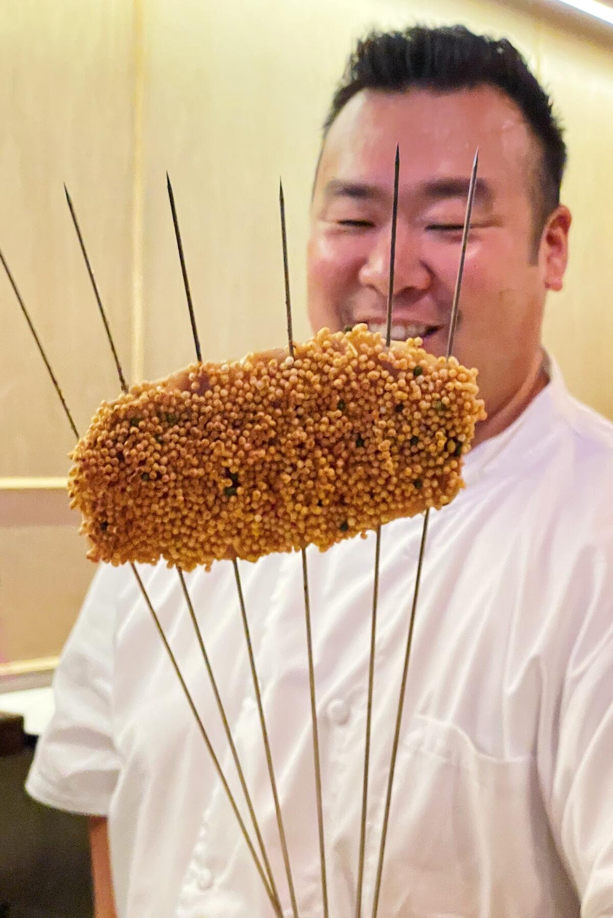 Daniel Son holds a piece of grilled fish coated in puffy rice crackers at Sushi Sonagi in Gardena