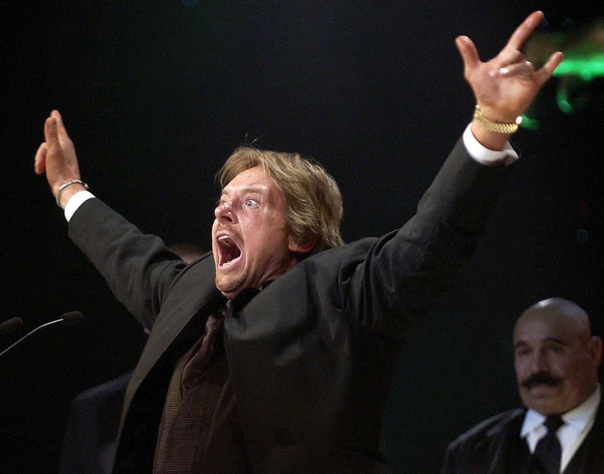 Rowdy Roddy Piper gestures to the crowd after being inducted into the WWE Hall of Fame at an April 2005 ceremony in Universal City, Calif.