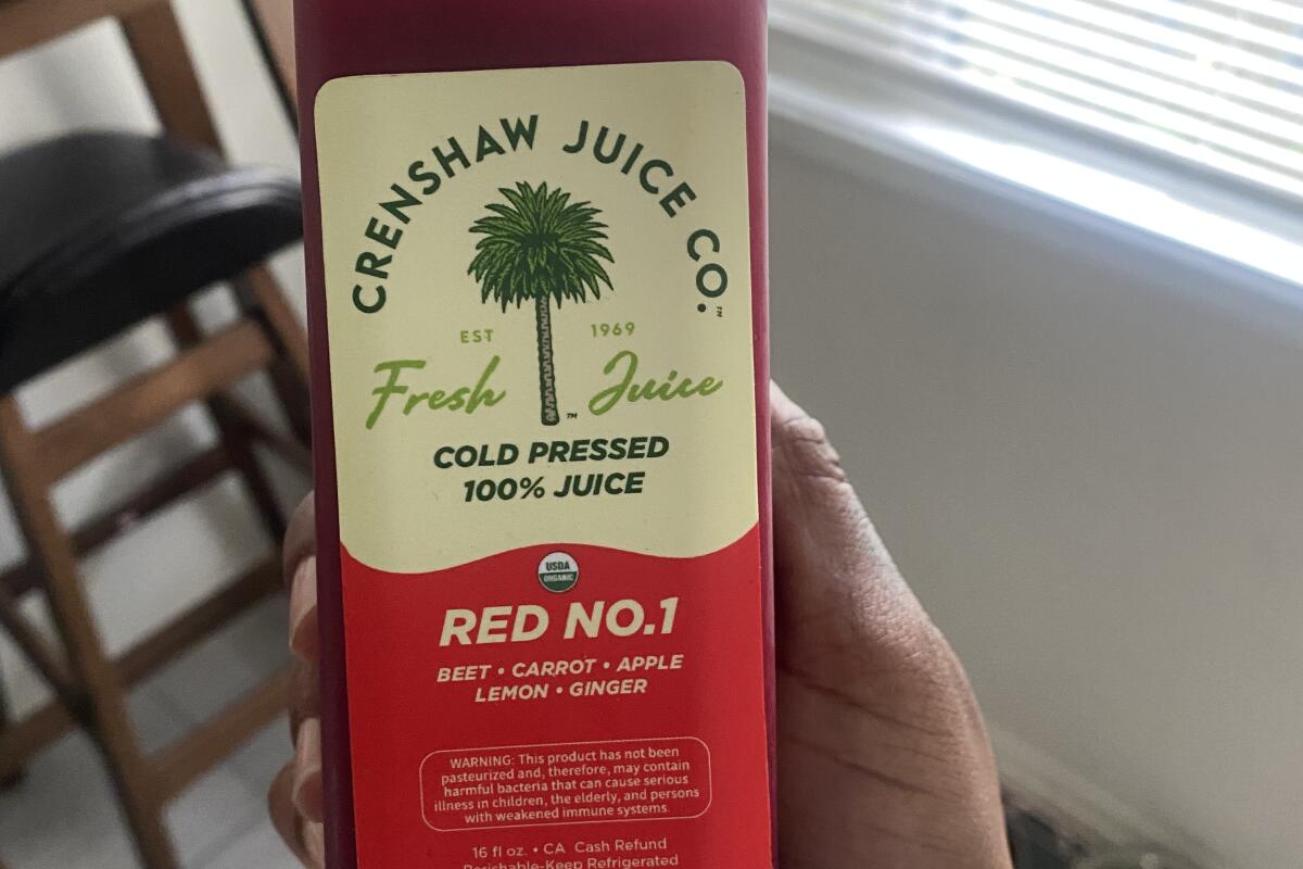 A hand holds up a bottle of Red No. 1 juice from Crenshaw Juice Co.
