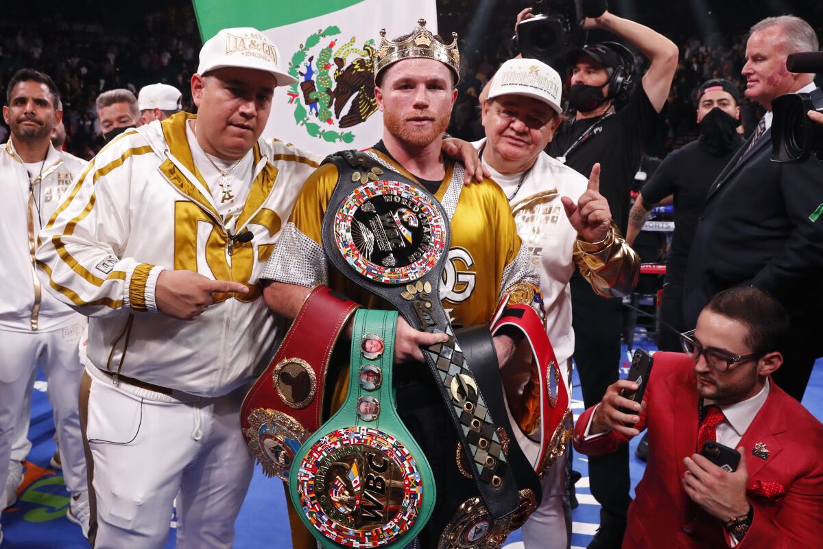 Canelo Álvarez poses with his trainers and his championship belts after defeating Caleb Plant on Saturday.