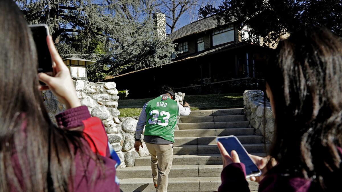 Jonathan Bugnosen of Northridge wears his Boston Celtics Larry Bird jersey while posing at the "Bird Box" house in Monrovia as his daughters Madden Bugnosen, 12, left, and Jianna Valenzuela, 14, snap pictures.