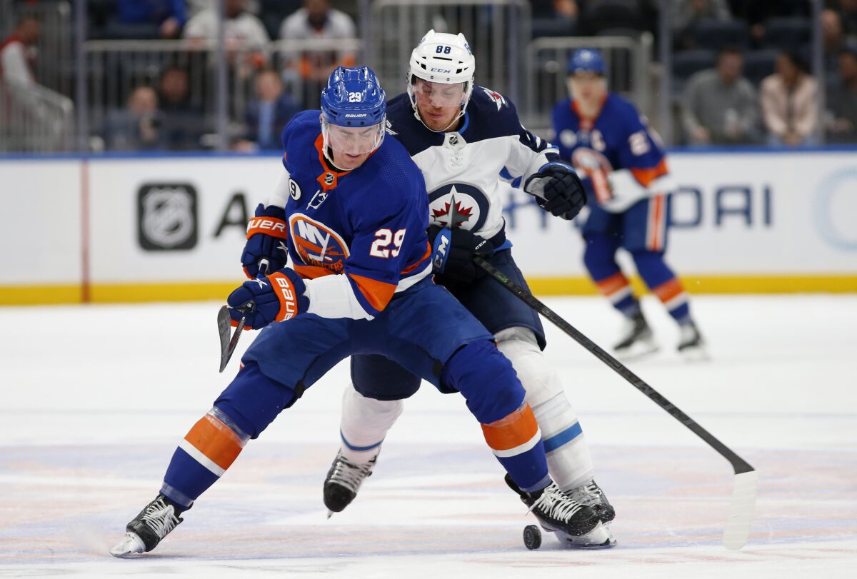 New York Islanders center Brock Nelson (29) tries to keep the puck from Winnipeg Jets defenseman Nate Schmidt (88) during the first period of an NHL hockey game on Friday, March 11, 2022, in Elmont, N.Y. (AP Photo/Jim McIsaac)