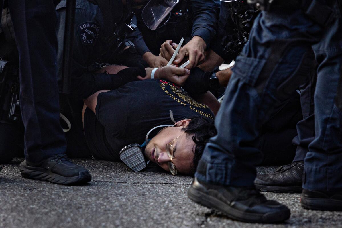 a man lays face down as a group of officers detain him