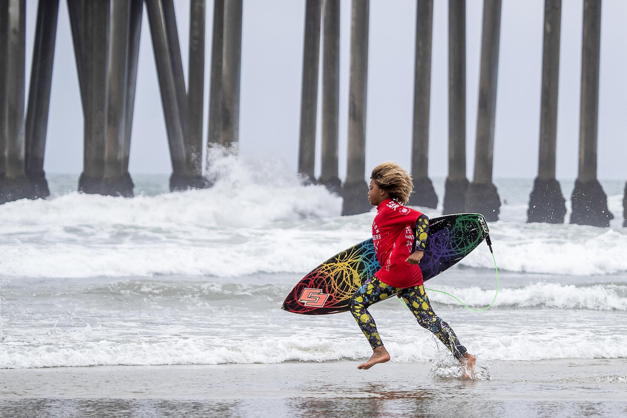 A child with a surfboard runs into the ocean.