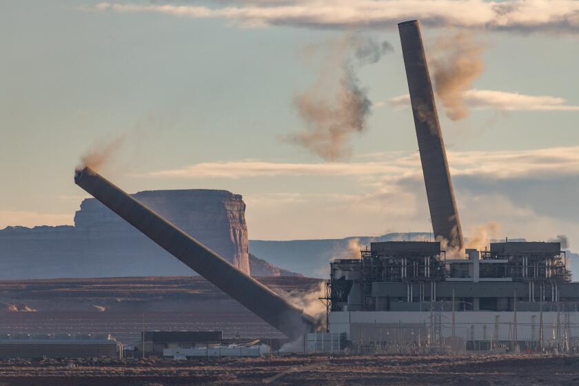 Two of the three smokestacks at Navajo Generating Station outside Page, Ariz., come tumbling down on Dec. 18, 2020.