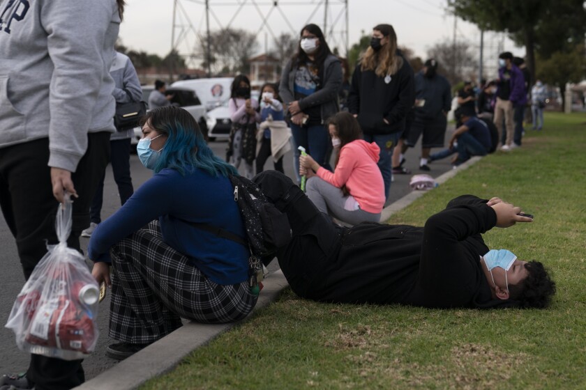 Robert Rodriguez, 14, looks at his phone while waiting in line for a test at a mobile COVID-19 testing site in Paramount, Calif., Wednesday, Jan. 12, 2022. (AP Photo/Jae C. Hong)