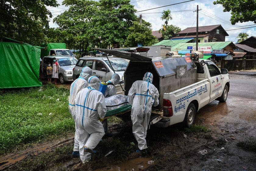 Volunteers wearing personal protective equipment (PPE) carry the body of a victim of the Covid-19 coronavirus to a van to bring to a cemetery in Hlegu Township in Yangon on July 10, 2021. (Photo by Ye Aung THU / AFP) (Photo by YE AUNG THU/AFP via Getty Images)